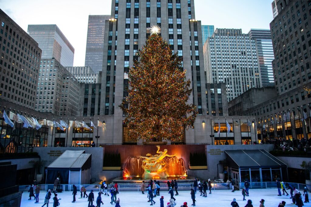 The iconic Rockefeller Christmas Tree glowing brightly at night, surrounded by the festive hustle and bustle of New York City—an essential stop on your Christmas bucket list.