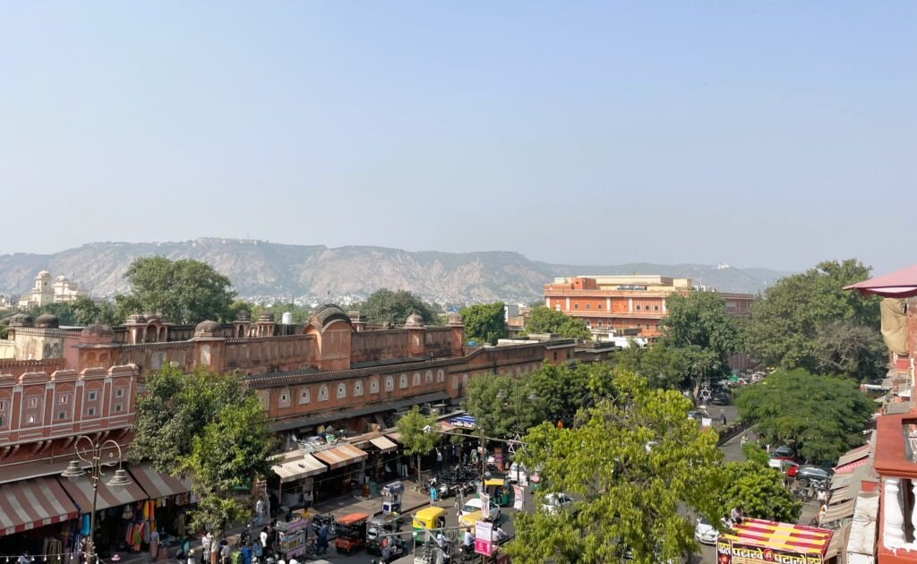 Panoramic view of Jaipur's old city from a rooftop cafe, with colorful buildings and the mountains in the background