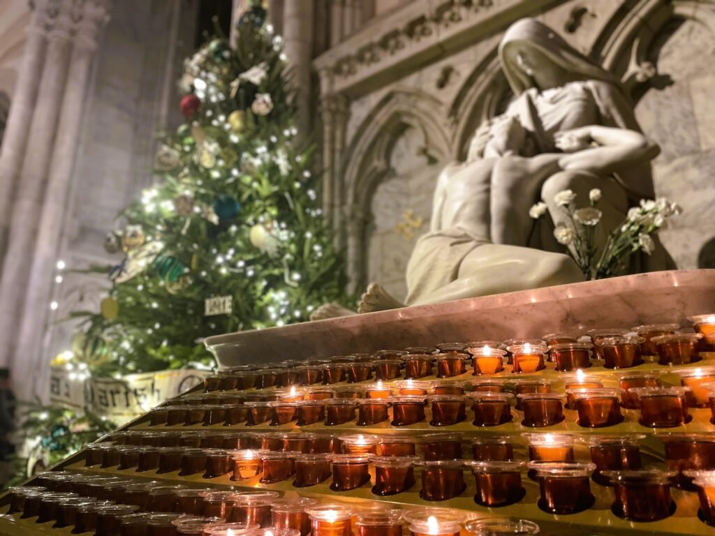 A serene view of lit candles and a statue inside St. Patrick's Cathedral, offering a peaceful moment amid the festive chaos of New York City—a hidden gem on your Christmas bucket list.